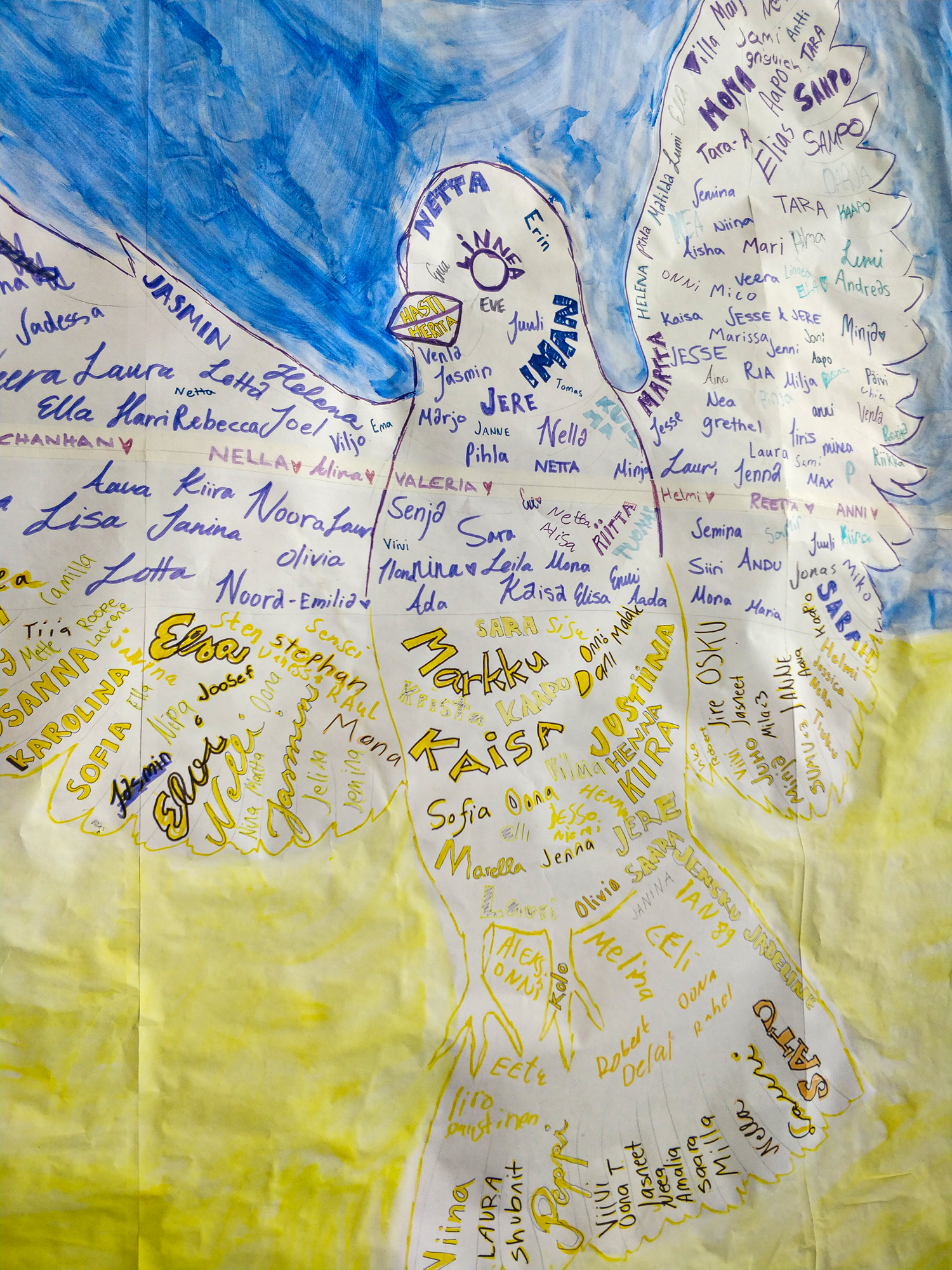 Kuvassa on piirretty rauhankyyhky, johon on kirjoittu nimiä. taustalla Ukrainan lipun värit.